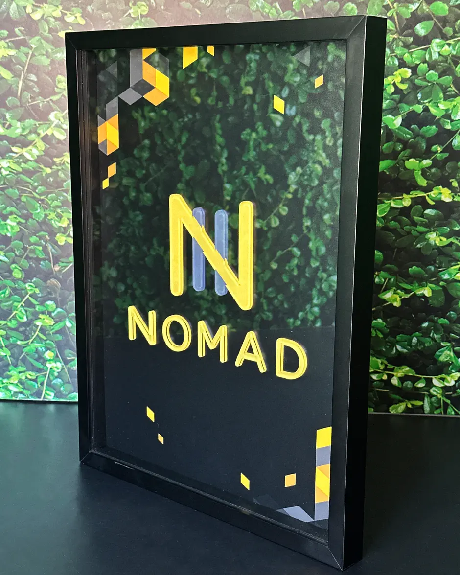 Quadro de premiação da Nomad, moldura preta com a marca em relevo dourado